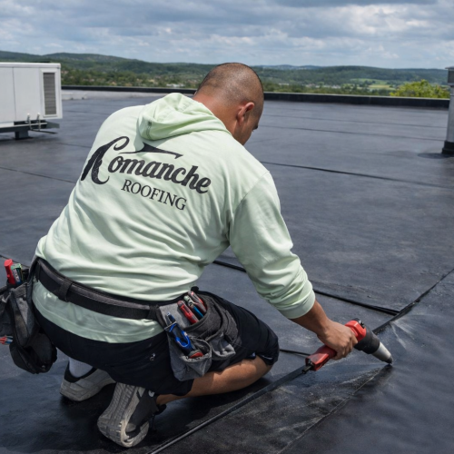 Worker installing EPDM roofing material.